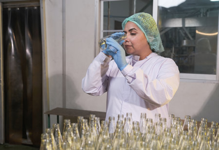 South asia senior woman factory worker or expert quality staff is checking bottles line for beverageの写真素材