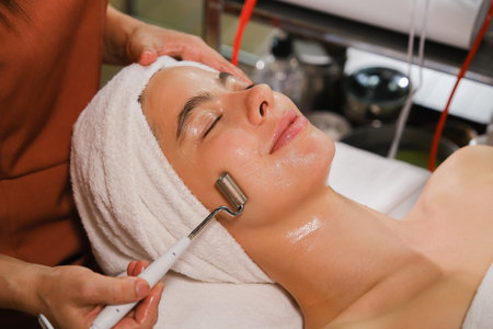 Woman in a beauty salon receiving a facial massage by a beauticianの写真素材