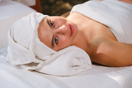 Portrait of a beautiful young woman lying on massage table at spa centerの写真素材
