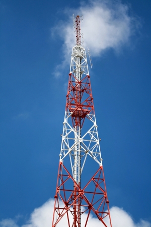 Telecommunications tower, painted white and red with blue sky の写真素材
