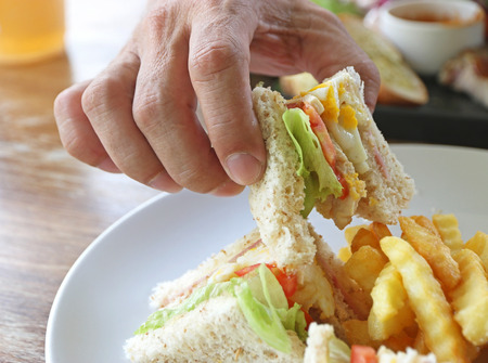 Big hand pick up piece of Club sandwich and potato friedの写真素材