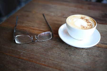 Workspace eye glasses and coffee cup on wood table