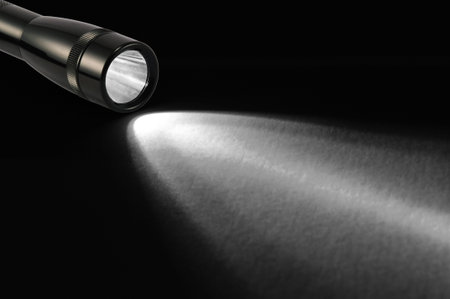 Black flashlight and shaft on black background.