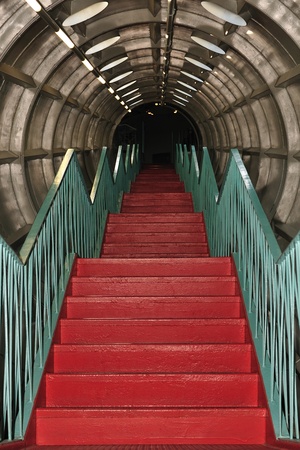 Close up of metal red steps in tube leading into the dark.  の写真素材