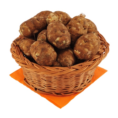 Wicker basket of sunchokes on orange cloth isolated on white.の写真素材