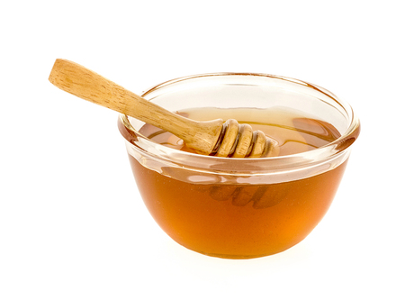 Wooden honey dipper with honey isolated on white backgroundの写真素材