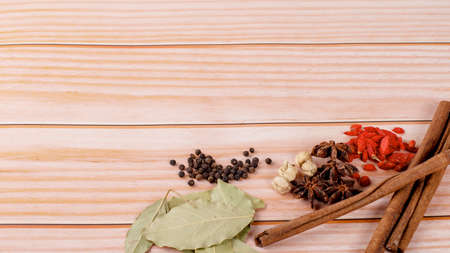 Exotic herbal Food concept Mix of the organic Spices cinnamon stick, cardamom pods, bay leaves, star anise isolated on wood backgroundの写真素材