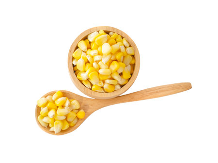 sweet corn in wooden bowl and spoon isolated on white background. top view