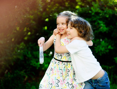 Children play together. Boy embraces girl and together look towards. Children playing.