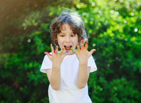 The boy enthusiastically watching his hands. His hands in the paint. The boy likes to drawの写真素材