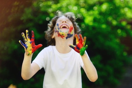 The boy's face and hands in the paint. He is happy about it. The child is happy. He likes the paint.の写真素材