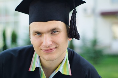 The young man with a smile looking at the camera. He has an academic cap on his headの写真素材
