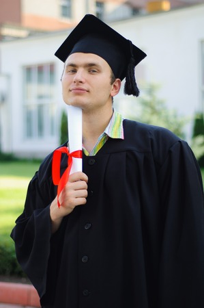 Student with a white scroll in her hand looking at the camera at his graduation ceremony.の写真素材