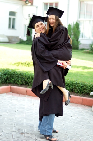 Graduates in the mantle embrace and enjoy. Beautiful graduate girl and boy enjoyed the ceremony graduation.の写真素材
