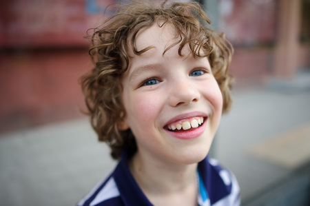 The blue-eyed boy smiling. He has blond hair disheveled. On the face broad smileの写真素材