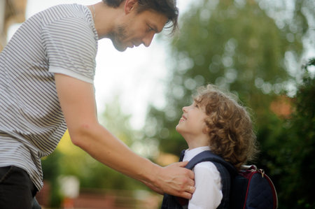 The father sends in school of the son-first-grader. It carefully corrects for a backpack of the boy....