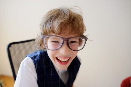 Funny little schoolboy in huge glasses carelessly laughing. He has a great mood. This elementary school student.の写真素材