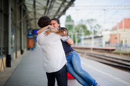 Joyful meeting at the railway station. The young man lifted the girl. Couple hugging. The girl has closed eyes with happiness.の写真素材