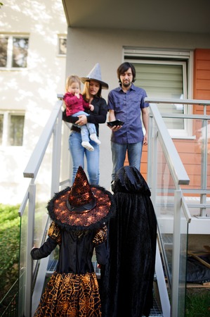 Trick or Treat. Two children in suits of evil forces have come to demand sweet. The young family friendly meets children on a threshold of the house. Sweets are received. Children love Halloween.の写真素材