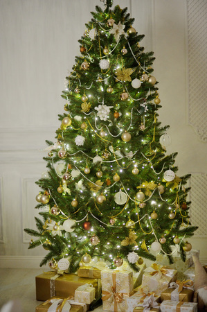 Elegant Christmas tree decorated with glistening glass balls, a beads and fairy lights. Under a fir-tree the mountain of Christmas gifts in beautiful packings.の写真素材