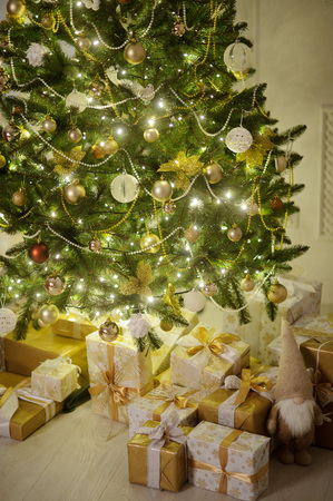 Elegant Christmas tree decorated with glistening glass balls, a beads and fairy lights. Under a fir-tree the mountain of Christmas gifts in beautiful packings.の写真素材