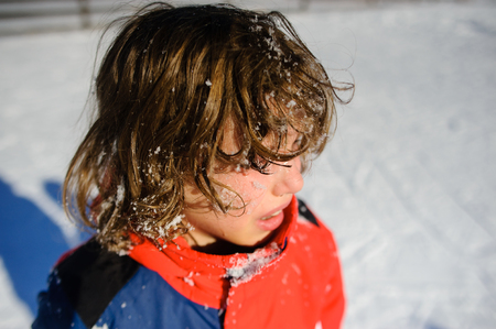 The boy of 9-10 years cries with pain or offense. The child without headdress. He all in snowの写真素材