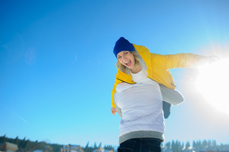 Young man holding in his arms his girlfriend. Man sturdily built easily picks up a fragile girl. Young people having fun. Against the background of the blue sky.の写真素材