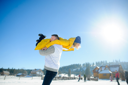 Young man holding in his arms his girlfriend. Man sturdily built easily picks up a fragile girl. Young people having fun. Against the background of the blue sky.の写真素材