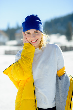 Portrait of the charming young woman. Sunny day, blue sky. The woman removes the bright yellow down-padded coat. To her hot and cheerfully.の写真素材
