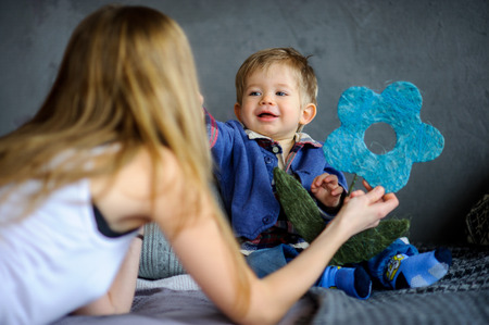 Mother plays with the little son. She shows him a toy. The kid with delight look at mother.の写真素材