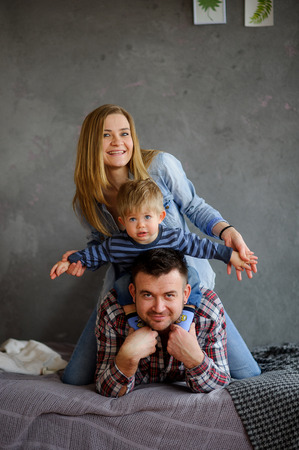 Family portrait. Young family of three people. Father, mother and small child. All have happy faces.の写真素材