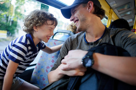 The young man goes by the bus together with the son. The father and the son sit next with each other...