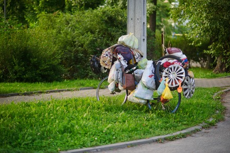 The ragman's bicycle on a green lawn. Lonely standing bike with plenty of old unnecessary things. Contrast with fresh young greens.の写真素材