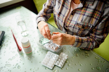 The woman having rheumatoid arthritis takes medicine. Hands are deformed.の写真素材