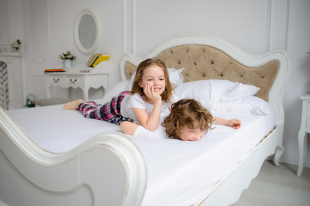 Brother and sister of primary school age play pranks on a bed. Them it is very cheerful.の写真素材