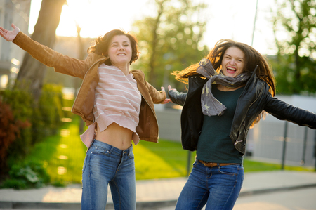 Two cheerful young women. Girlfriends dance. Wonderful spring day. Excellent mood.の写真素材