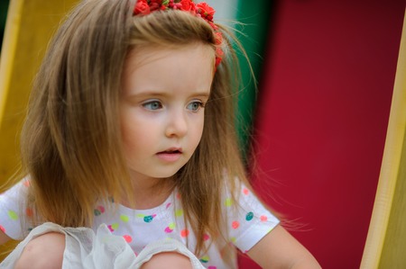 Portrait of the charming girl of 4-5 years. Beautiful long fair hair. A wreath from red colors on the head. Expressive gray-blue eyes. Bright lips.の写真素材