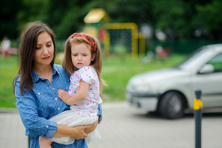 The young woman holds the little daughter on hands. Mother gently embraces the child.の写真素材