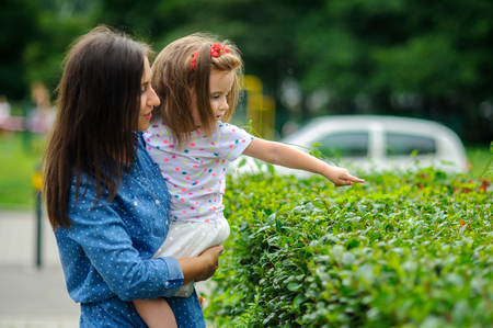 The young woman holds the little daughter on hands. Mother gently embraces the child.の写真素材