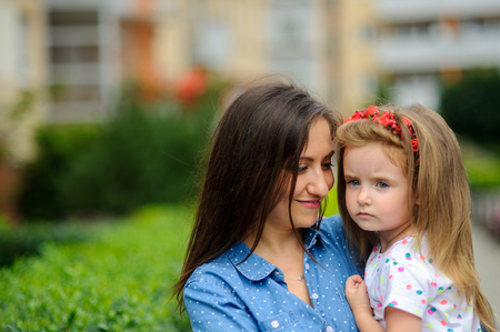 The young woman holds the little daughter on hands. Mother gently embraces the child.の写真素材