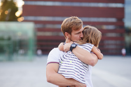 Young father holds the little daughter on hands. Man gently presses to himself the child.の写真素材