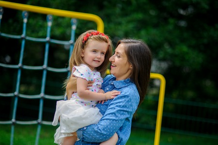 The young woman holds the little daughter on hands. Mother gently embraces the child.の写真素材