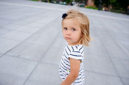 Portrait of a two year old girl in a striped dress. Nice face, short blond hair, serious look.の写真素材