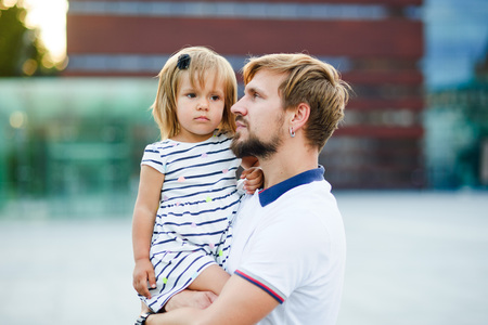 Young father holds the little daughter on hands. Man gently presses to himself the child.の写真素材