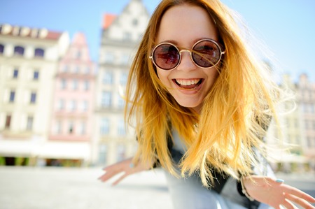 Charming young girl in sunglasses against the backdrop of a beautiful old building.の写真素材