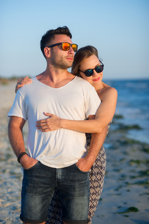 Couple of lovers stands having embraced on the seashore. Sunset, sea waves. Romantic rendezvous.の写真素材