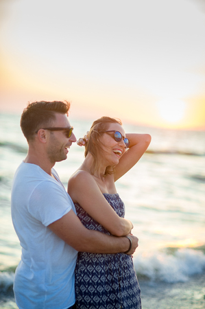 Couple of lovers stands having embraced on the seashore. Sunset, sea waves. Romantic rendezvous.の写真素材
