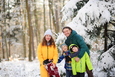Family portrait in the winter forest. Happy family together with a pet against the background of snow-covered trees.の写真素材