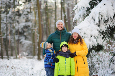 Family portrait in the winter forest. Happy family against the background of snow-covered trees.の写真素材
