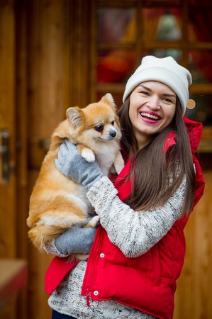 Cheerful young woman with a pet. Owner holds of a little pomeranian spitz. Woman has a good mood.の写真素材